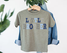 Load image into Gallery viewer, A gray t-shirt with the text "LITTLE BROTHER" printed on it, hanging on a clothing hanger.