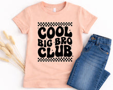 Load image into Gallery viewer, A pink t-shirt with the text "COOL BIG BRO CLUB" printed on it, along with a pair of blue jeans.