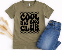 Load image into Gallery viewer, A green t-shirt with the text "COOL BIG BRO CLUB" printed on it, along with a pair of blue jeans.