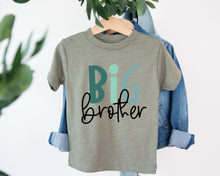 Load image into Gallery viewer, A gray t-shirt with the text "BIG brother" printed on it, hanging on a wooden hanger.