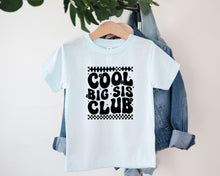 Load image into Gallery viewer, A white t-shirt with the text "COOL BIG SIS CLUB" printed on it, hanging on a wooden hanger.