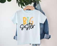 Load image into Gallery viewer, A white t-shirt with the text "BIG SISTER" printed on it, hanging on a clothing hanger.