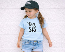 Load image into Gallery viewer, A young girl wearing a blue t-shirt with the text "big SIS" and a black baseball cap stands against a white wall.