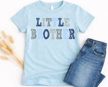 Load image into Gallery viewer, A light blue t-shirt with the text "LITTLE BROTHER" printed on it, along with a pair of blue jeans.