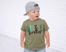 Load image into Gallery viewer, A young child wearing a gray baseball cap and a green t-shirt with the text "Little brother" printed on it, standing in front of a white brick wall.
