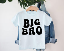 Load image into Gallery viewer, A white t-shirt with the text "BIG BRO" printed on it, hanging on a clothing hanger.