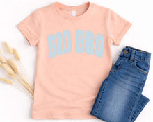 Load image into Gallery viewer, A pink t-shirt with the text "BIG BRO" printed on it, along with a pair of blue jeans, are laid out on a white background.