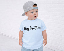 Load image into Gallery viewer, A young child wearing a gray baseball cap and a light blue t-shirt with the text "big brother" printed on it, standing in front of a white brick wall.