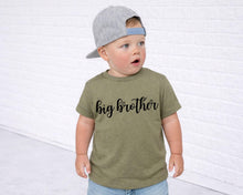 Load image into Gallery viewer, A young child wearing a gray baseball cap and a green t-shirt with the text "big brother" printed on it, standing in front of a white brick wall.