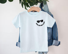 Load image into Gallery viewer, A light blue t-shirt with a graphic design and text printed on it, hanging on a clothing hanger.