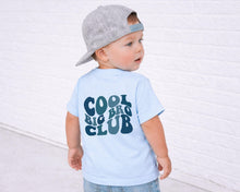 Load image into Gallery viewer, A young child wearing a gray baseball cap and a light blue t-shirt with the text "COOL BIG CLUB" printed on it, standing in front of a white brick wall.