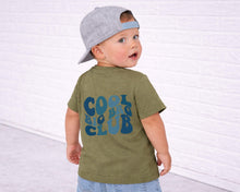 Load image into Gallery viewer, A young child wearing a green t-shirt with the text "COOL BIG CLUB" printed on it, along with a gray baseball cap.