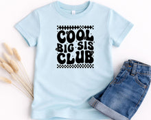 Load image into Gallery viewer, A light blue t-shirt with the text "COOL BIG SIS CLUB" printed on it, along with a pair of denim shorts.