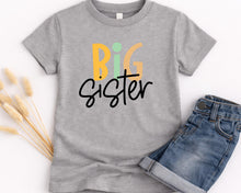 Load image into Gallery viewer, A gray t-shirt with the text "BIG SISTER" printed on it, along with a pair of blue jeans.