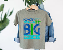 Load image into Gallery viewer, A gray t-shirt with a graphic design that says "PROMOTED TO BIG BROTHER" in blue and green text.
