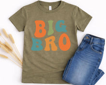 Load image into Gallery viewer, A green t-shirt with the text "BIG BRO" printed on it, along with a pair of blue jeans.
