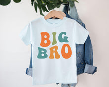 Load image into Gallery viewer, A white t-shirt with the text "BIG BRO" printed on it, hanging on a clothing hanger.
