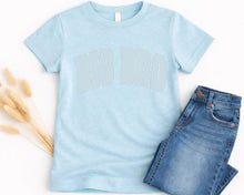 Load image into Gallery viewer, A light blue t-shirt with the text "BIG BRO" printed on it, along with a pair of blue jeans, are displayed on a white background.
