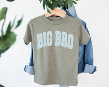 Load image into Gallery viewer, A gray t-shirt with the text "BIG BRO" printed on it, hanging on a wooden hanger.
