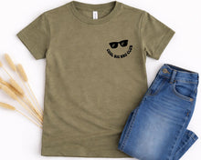 Load image into Gallery viewer, A green t-shirt with a graphic design and text, along with a pair of blue jeans, are displayed on a white background.
