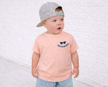 Load image into Gallery viewer, A young child wearing a gray baseball cap and a pink t-shirt with sunglasses and the text "BIG BROTHERS" stands in front of a white brick wall.
