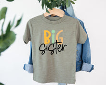 Load image into Gallery viewer, A gray t-shirt with the text "BIG Sister" printed on it, hanging on a clothing hanger.
