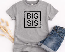 Load image into Gallery viewer, A gray t-shirt with the text "BIG SIS" printed on it, along with a pair of blue jeans.
