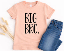 Load image into Gallery viewer, A pink t-shirt with the text "BIG BRO" printed on it, along with a pair of blue jeans, are displayed on a white background.
