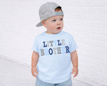 Load image into Gallery viewer, A young child wearing a gray baseball cap and a light blue t-shirt with the text "Little Brother" printed on it, standing in front of a white brick wall.
