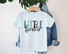 Load image into Gallery viewer, A white t-shirt with the text "Little Brother" printed on it, hanging on a clothing hanger.

