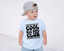 Load image into Gallery viewer, A young child wearing a gray baseball cap and a light blue t-shirt with the text "COOL BIG BRO CLUB" printed on it.
