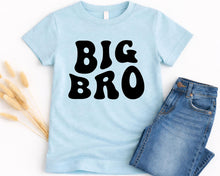 Load image into Gallery viewer, A light blue t-shirt with the text "BIG BRO" printed on it, along with a pair of blue jeans.
