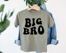 Load image into Gallery viewer, A gray t-shirt with the text "BIG BRO" printed on it, hanging on a clothing hanger.
