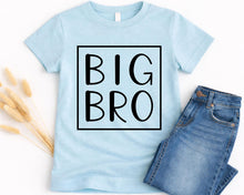 Load image into Gallery viewer, A light blue t-shirt with the text "BIG BRO" printed on it, along with a pair of blue jeans.
