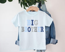 Load image into Gallery viewer, A light blue t-shirt with the text "BIG BROTHER" printed on it, hanging on a clothing hanger.

