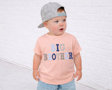 Load image into Gallery viewer, A young child wearing a gray baseball cap and a pink t-shirt with the text "BIG BROTHER" standing in front of a white brick wall.
