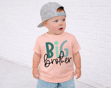 Load image into Gallery viewer, A young child wearing a gray cap and a pink t-shirt with the text "Big brother" printed on it, standing in front of a white brick wall.
