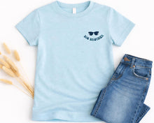 Load image into Gallery viewer, A light blue t-shirt with a graphic of sunglasses and the text "Big brother" printed on it, along with a pair of blue jeans.
