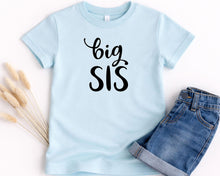 Load image into Gallery viewer, A light blue t-shirt with the text "big SIS" printed on it, along with a pair of denim shorts.
